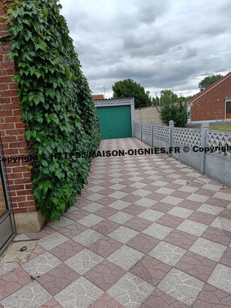 l'image montre une allée large pour entrée de voitures vers le garage et accès arrière à la maison et au jardin