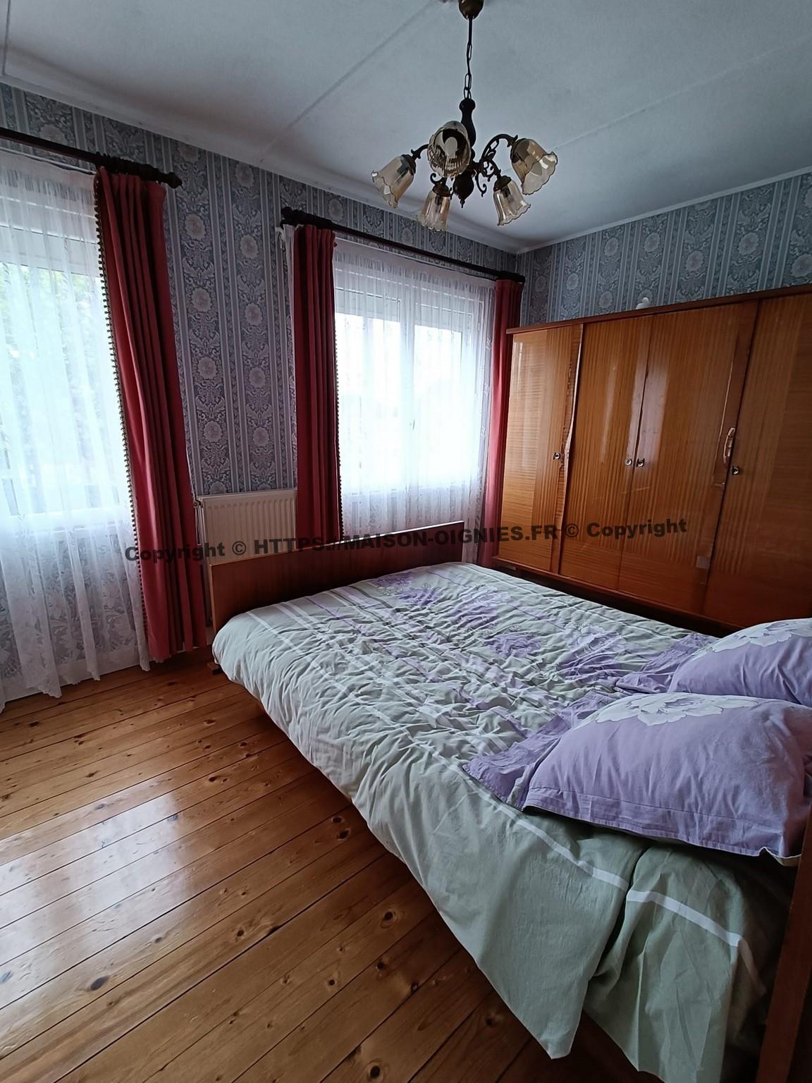 l'image montre la chambre avant, de trois quart depuis la porte, avec son plancher bois vitrifié, un lit 140 et une armoire tous deux vernis et de style ancien 60's